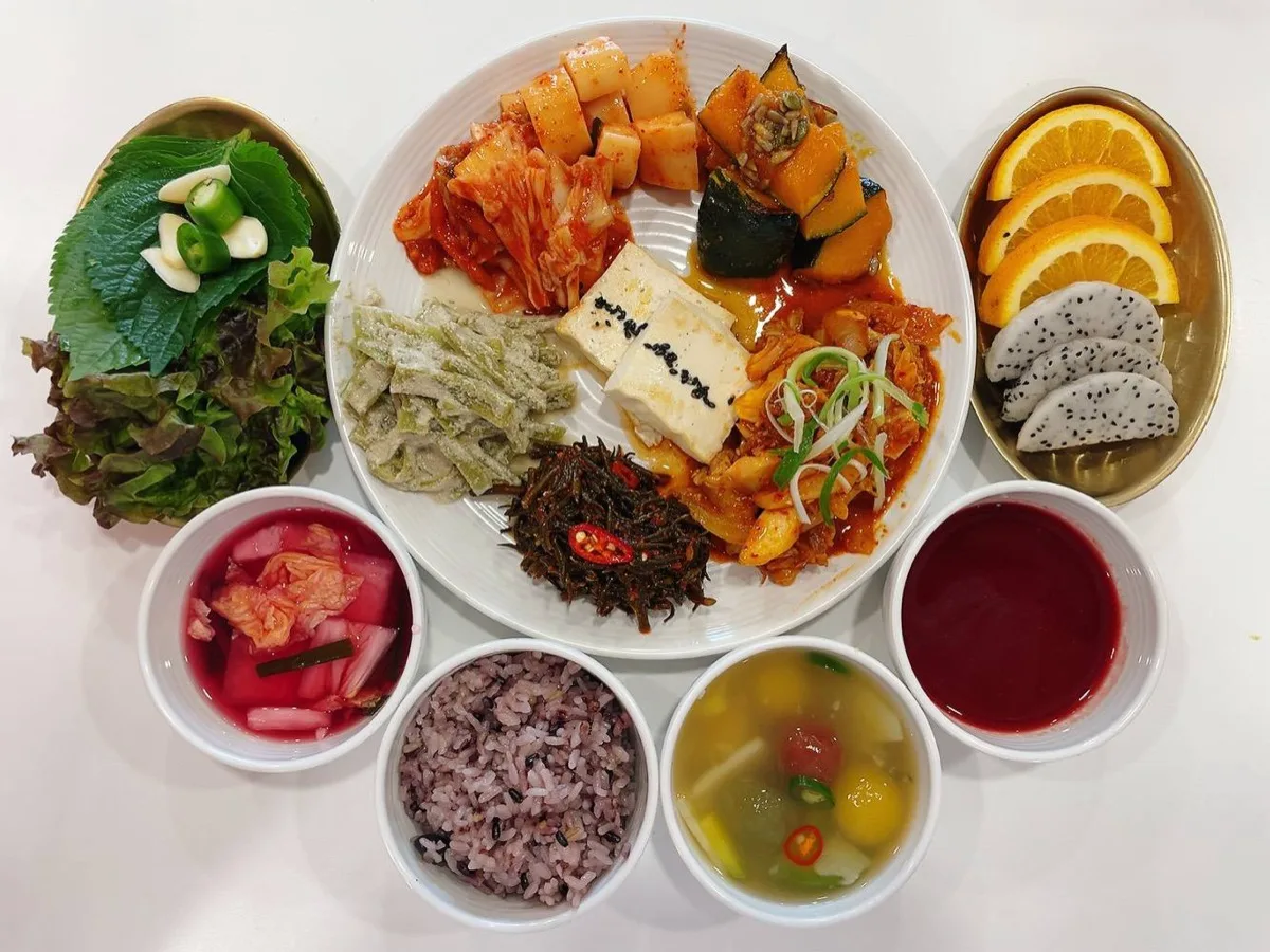 식단 구성 — 흑미 잡곡밥, 두부김치, 단호박조림, 무생채, 고사리나물, 상추·깻잎 쌈채소, 배추김치, 감자국, 과일 주스, 물김치, 오렌지·용과